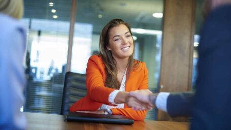 a young graduate sits across the table from her interview panel  full of confidence and positivity energy . She is holding he
