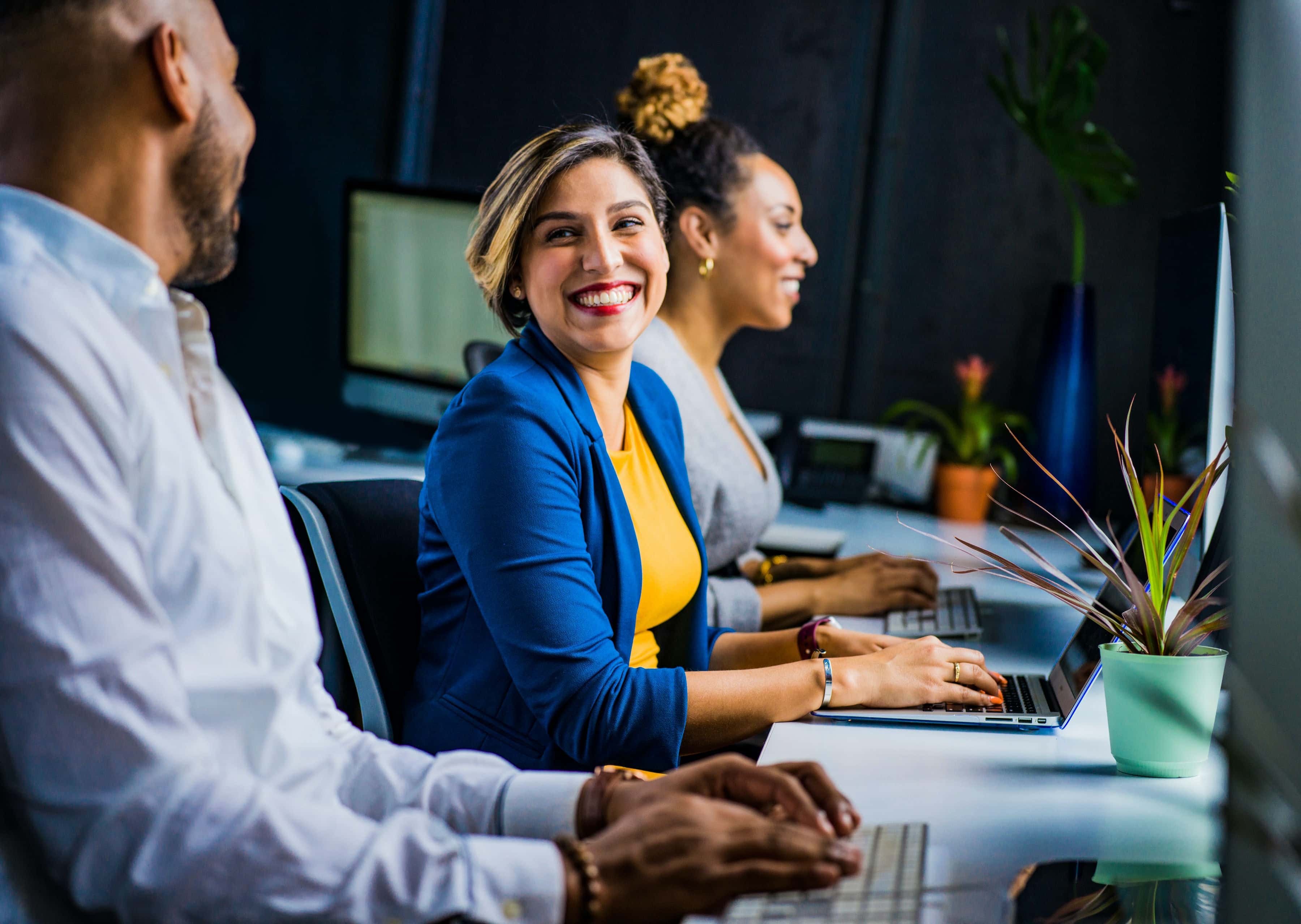 Woman in Blue Suit Jacket smiling at coworker