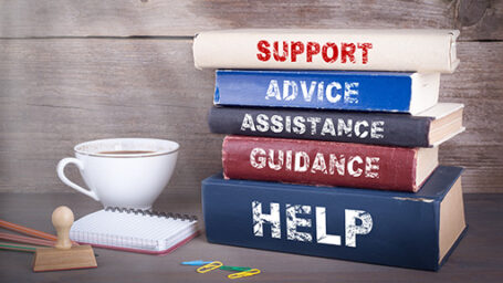 Support concept. Stack of books on wooden desk. a stack of books that say 