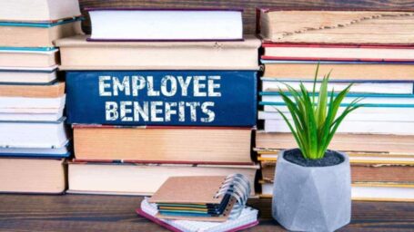 stack of books and a plat. words reading employee benefits on a book