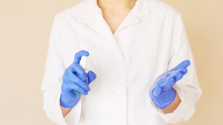 person in white coat and blue latex gloves