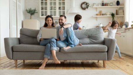 People sitting on a couch with kids running in the background