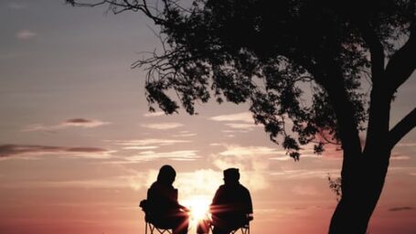 two people sitting in chairs at sunset